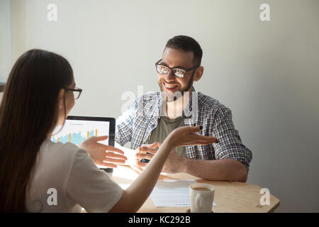 Due imprenditori amichevole a discutere i dettagli del contratto. femmina spiega agente contratto, trattare, prestito dettagli per uomo sorridente. collaboratori negoziando, pla Foto Stock