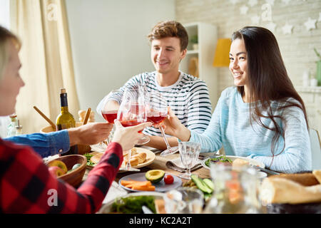 Ritratto di gruppo di amici di gustare la cena insieme seduti al grande tavolo con delizioso cibo , concentrarsi sul giovane e bella donna asiatica happil sorridente Foto Stock