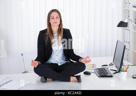 Bella giovane imprenditrice fare yoga in ufficio Foto Stock