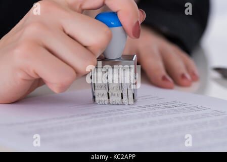 Close-up di commercianti mano utilizzando stamper sul documento Foto Stock