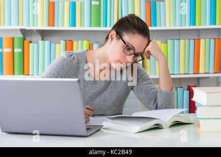 Foto di giovane donna studiare in biblioteca Foto Stock