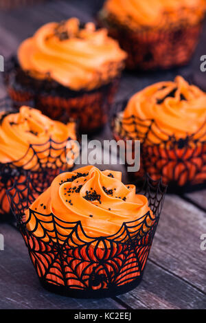 Arancione tortini di halloween con nero spruzza sul tavolo rustico Foto Stock