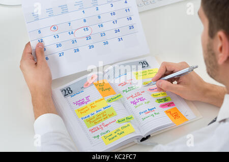 Close-up di imprenditore con calendario di pianificazione di scrittura nel diario Foto Stock