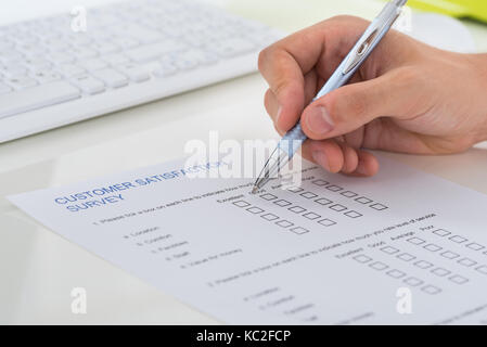 Close-up di persona le mani riempiendo il modulo del sondaggio con la penna Foto Stock