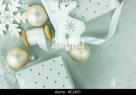 Confezioni regalo avvolto in carta argentata con la polka dots pattern. lo stelo di legno con il bianco arricciato nastro di seta, baubles di natale, renne abete ornamento Foto Stock