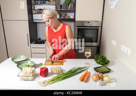 Ragazza carota di taglio e di preparazione per il wok vegetale Foto Stock