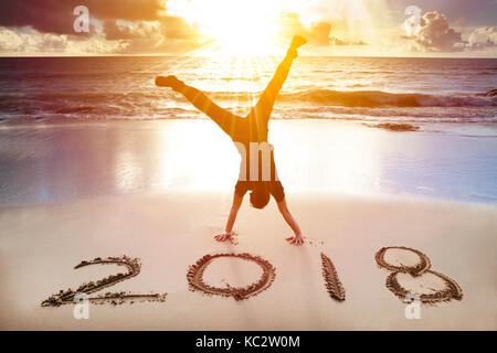 L'uomo handstand sulla spiaggia.felice anno nuovo 2018 concept Foto Stock