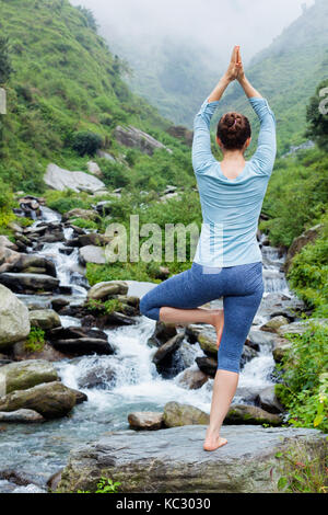 La donna a Yoga asana Vrikshasana posizione dell'albero a cascata all'aperto Foto Stock