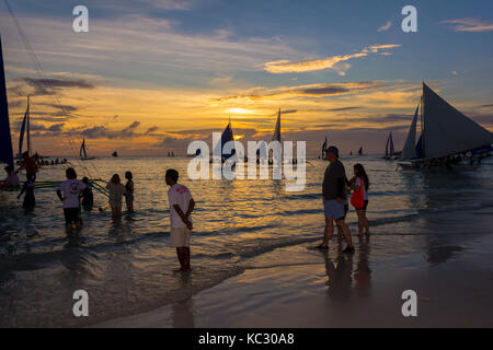 Il Boracay, Filippine - 16 SET 2015: beautiful Golden Sunset over barche da pesca e persone in acqua Foto Stock