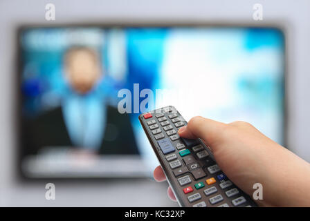 Man mano gli interruttori di canali tv. la natura astratta. telecomando in mano e tv Foto Stock