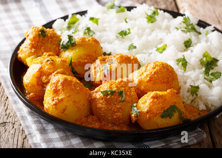 Il cibo indiano: dum, aloo patate in una salsa con riso close-up su una tavola orizzontale. Foto Stock