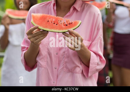 Irriconoscibile donna in maglia rosa azienda fetta di anguria fresca closeup Foto Stock