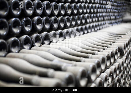 Impilati polverose bottiglie di champagne in cantina. Close up Foto Stock