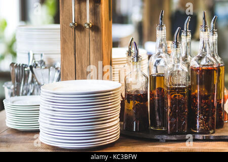 Set da cucina nel ristorante, posate, piatti e vari tipi di olio di oliva Foto Stock