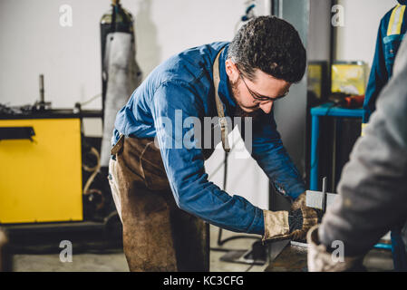 Saldatore controllo angolo di materiali saldati in officina Foto Stock