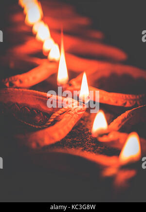 Felice diwali - molti diya in terracotta o lampade ad olio disposti sulla superficie di argilla o terra in una linea o curva o a zig-zag, il fuoco selettivo Foto Stock