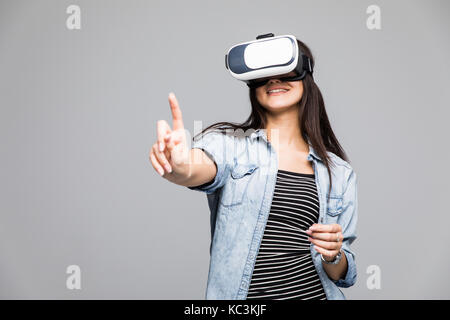 Giovane donna che indossa occhiali per realtà virtuale e rivolto verso l'alto con il suo dito indice con un espressione seria Foto Stock