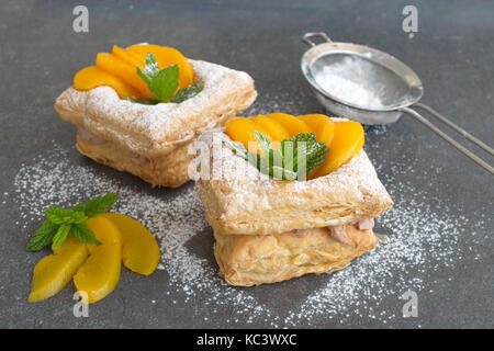 In casa di pasta sfoglia i biscotti con crema chocolade e conserve di albicocche su un nero sfondo astratto. Foto Stock