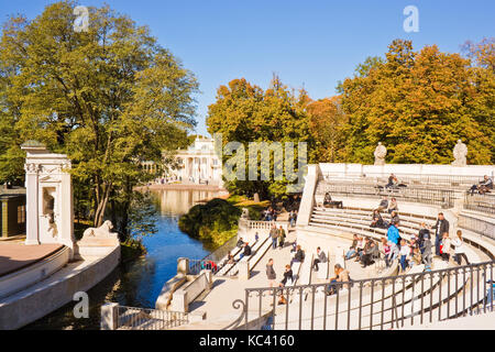 Varsavia, Polonia - 10 ottobre 2015: persone rilassante sui banchi dell'anfiteatro in krolewskie Lazienki Park (parco delle terme reali), l'acqua palac Foto Stock