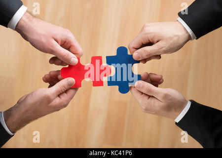 Immagine ritagliata di uomini di affari di assemblaggio di puzzle che rappresenta il lavoro di squadra in office Foto Stock