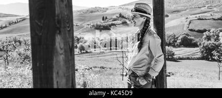 Alla scoperta di magiche vedute della Toscana. sorridente donna attiva escursionista in hat in toscana guardando in lontananza Foto Stock