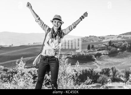 Alla scoperta di magiche vedute della Toscana. sorridente donna attiva escursionista in hat con sacchetto sulla Toscana Escursione gioia Foto Stock