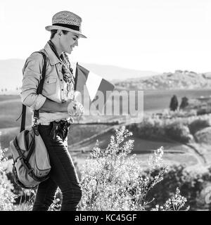 Alla scoperta di magiche vedute della Toscana. sorridente donna avventura escursionista in hat con bandiera italiana gode di vista in toscana Foto Stock