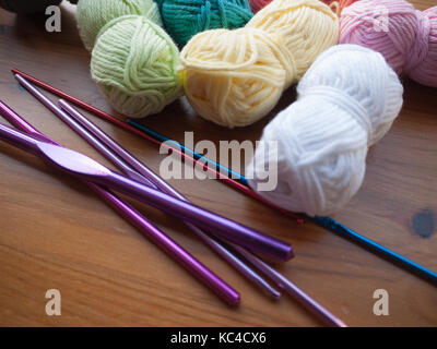Aghi da maglia e lana multicolore su una superficie in legno Foto Stock