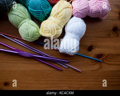 Aghi da maglia e lana multicolore su una superficie in legno Foto Stock