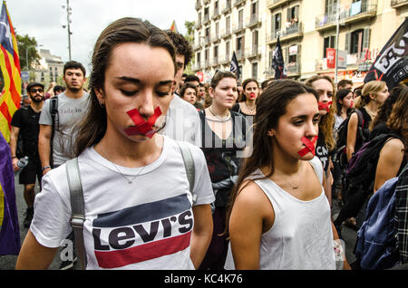 Barcellona, Spagna. 2 Ottobre, 2017. Gli studenti sono visto la bocca con nastro adesivo con una croce di colore rosso mentre si cammina attraverso la strada durante la protesta. Circa duemila studenti si sono riuniti per protestare contro la polizia scontri che è accaduto il 1 ottobre durante il Referendum in Catalogna. Credito: SOPA Immagini limitata/Alamy Live News Foto Stock