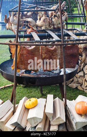 All'esterno la cottura di polli e carne di maiale a Daylesford fattoria biologica festa d'autunno. Daylesford, Cotswolds, Gloucestershire, Inghilterra Foto Stock