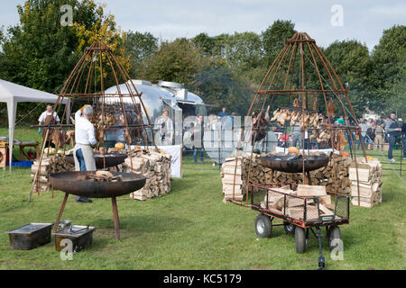 All'esterno la cottura di polli e carne di maiale a Daylesford fattoria biologica festa d'autunno. Daylesford, Cotswolds, Gloucestershire, Inghilterra Foto Stock