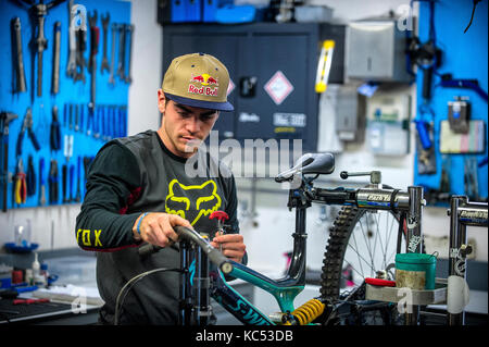 Professional downhill mountain biker Loïc Bruni. 2015 e 2017 UCI downhill mountain bike campione del mondo. Raffigurato in un edificio officina la sua moto. Foto Stock