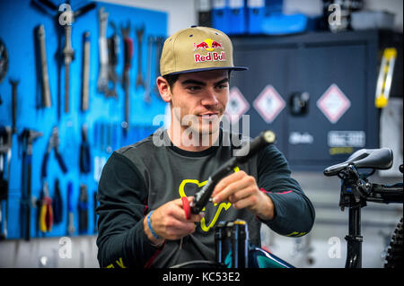 Professional downhill mountain biker Loïc Bruni. 2015 e 2017 UCI downhill mountain bike campione del mondo. Raffigurato in un edificio officina la sua moto. Foto Stock