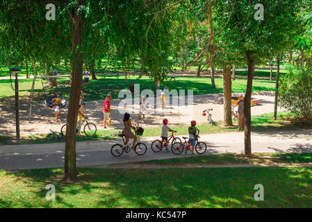 Famiglia in bicicletta estate, vista di una famiglia in bicicletta nel giardino del fiume Turia - i Jardines del Turia - Valencia, Spagna, Europa Foto Stock