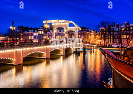 Skinny e il ponte sul fiume Amstel di Amsterdam Paesi Bassi al crepuscolo Foto Stock