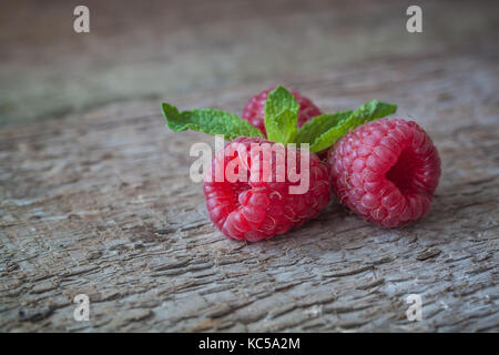 I lamponi con una foglia di menta sullo sfondo di legno. primo piano. Foto Stock