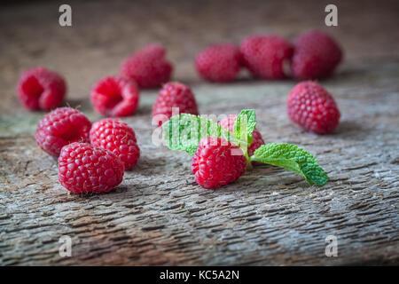I lamponi con una foglia di menta sullo sfondo di legno. primo piano. Foto Stock