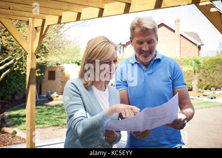 Donna matura guardando al piano di progettazione con paesaggio giardiniere Foto Stock