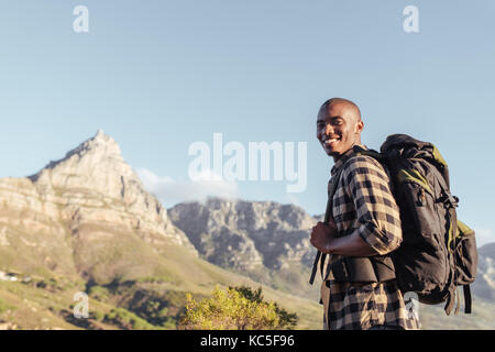 Sorridente giovane africano godendo la vista mentre fuori escursionismo Foto Stock