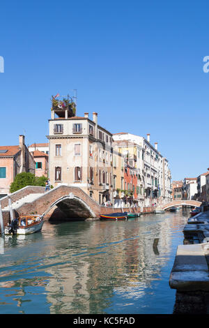 Rio dei Carmini, un pittoresco canale nel sestiere di Dorsoduro, Venezia, Veneto, Italia con colorati palazzi e riflessioni sull'acqua. Spazio di copia su un soleggiato Foto Stock