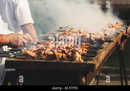 Stuzzicante fritto delizioso pezzi di carne su spiedini sono arrostite su un grande grill all'aperto. Lo chef prepara un barbecue. shish kebab national Foto Stock