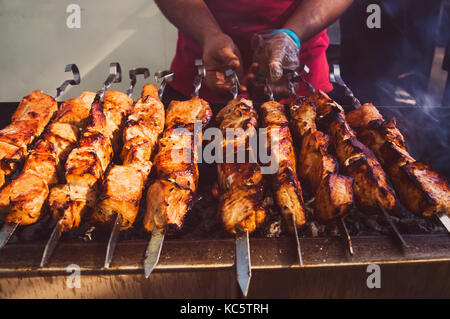 Stuzzicante fritto delizioso pezzi di carne su spiedini sono arrostite su un grande grill all'aperto. Lo chef prepara un barbecue. shish kebab national Foto Stock