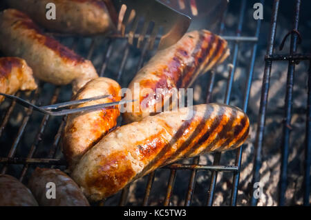 Misto di diverse varietà di deliziose char salsicce alla griglia su un barbecue all'aperto in giardino, vista da sopra, close-up Foto Stock