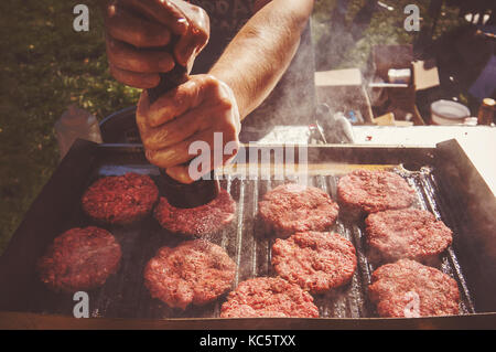 Lo chef prepara il pepe hamburger al barbecue esterno. cook sottaceti fritti fritti polpette di carne alla griglia Foto Stock