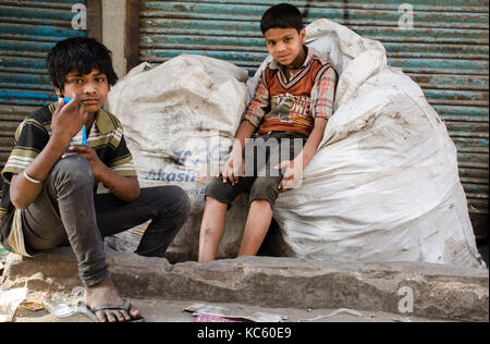 New Delhi, India - 23 aprile 2016 : ritratto di due ragazzi indiani seduti sui sacchi della spazzatura Foto Stock