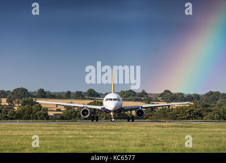 La Monarch Airlines airbus a321 g-ozbm rullaggio di fronte un arcobaleno come una tempesta passa il 18 agosto 2017 a Londra Luton, Bedfordshire, Regno Unito Foto Stock