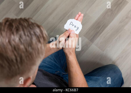 Uomo in possesso di un pezzo di carta con il testo pregare nella Sua mano Foto Stock