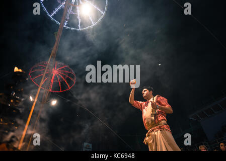 Varanasi, India - 13 marzo 2016: immagine orizzontale di indù non identificato uomo indiano cercando di fiori durante i religiosi ganga aarti rituale a da Foto Stock