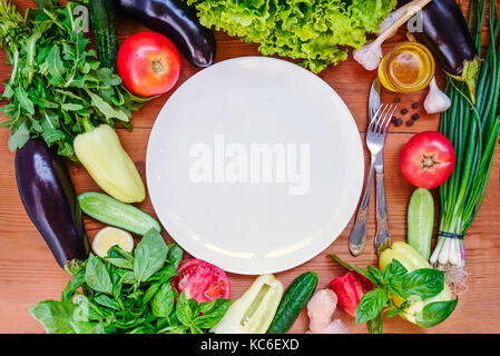 Vista superiore fresche verdure organiche - Ingredienti per insalata e bianco piastra vuota .dieta, detox, stile di vita vegetariano concetto . Il fuoco selettivo.spazio testo foc. Foto Stock